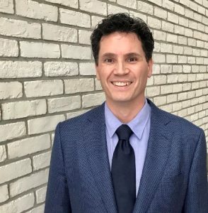 dr michael lang standing in a blue suit against a brick wall