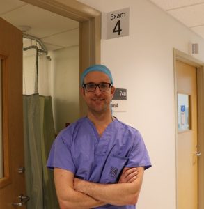 dr yardley standing in a hospital hallway in scrubs